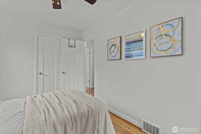 bedroom with a ceiling fan, baseboards, visible vents, and wood finished floors