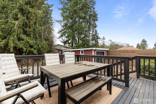 wooden terrace featuring a fenced backyard, an outdoor structure, and outdoor dining space