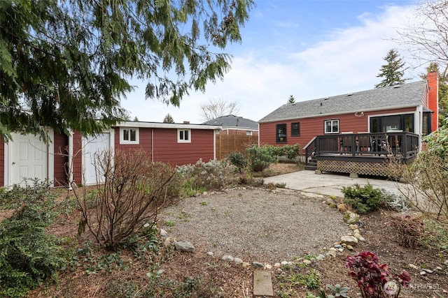 rear view of house with a chimney, a patio area, fence, and a deck