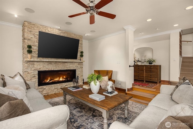 living area featuring baseboards, ornamental molding, wood finished floors, stairs, and a fireplace