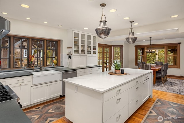 kitchen featuring stainless steel dishwasher, a healthy amount of sunlight, decorative light fixtures, and a center island