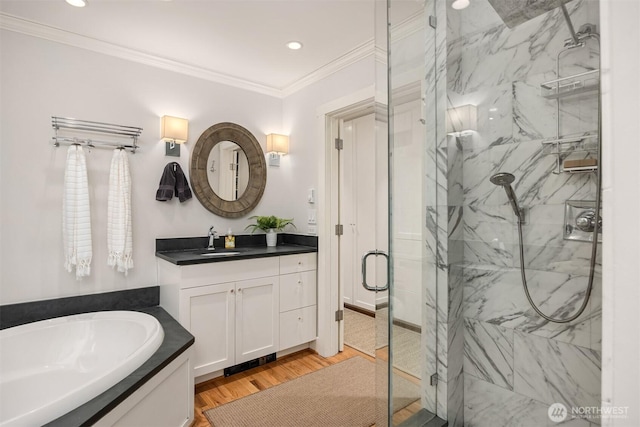 bathroom with a marble finish shower, ornamental molding, wood finished floors, vanity, and a bath