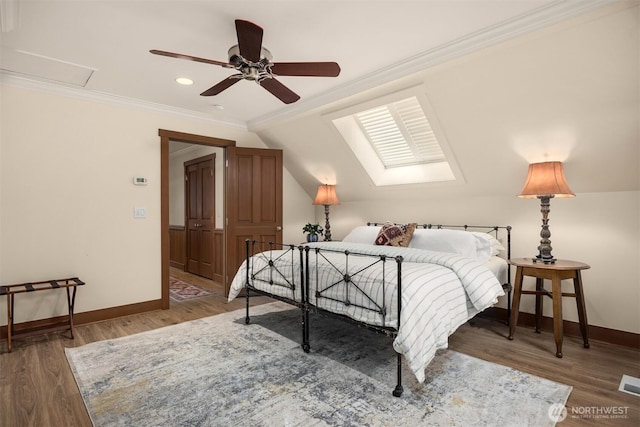 bedroom featuring lofted ceiling, visible vents, ornamental molding, wood finished floors, and baseboards