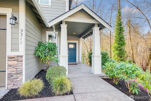 view of exterior entry with stone siding and a porch