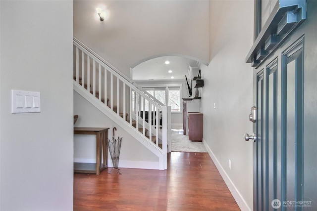 entrance foyer with arched walkways, recessed lighting, wood finished floors, baseboards, and stairs