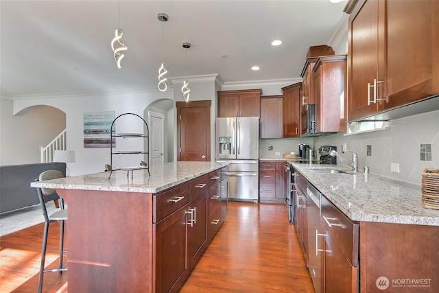 kitchen with a kitchen bar, appliances with stainless steel finishes, arched walkways, and a sink