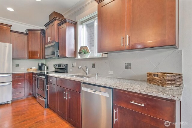 kitchen with stainless steel appliances, tasteful backsplash, a sink, and ornamental molding