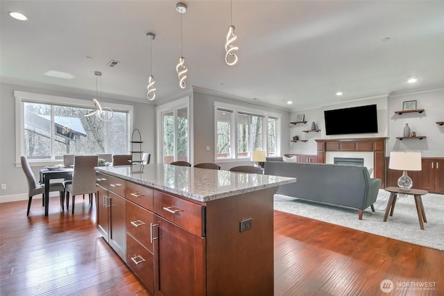 kitchen with light stone countertops, dark wood-style floors, ornamental molding, and a wealth of natural light