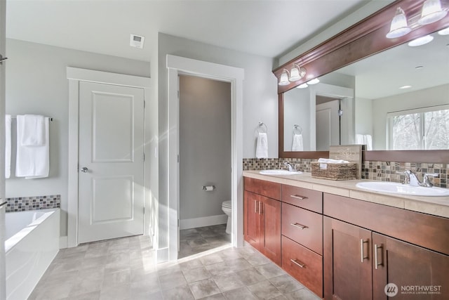 full bath featuring toilet, tasteful backsplash, visible vents, and a sink