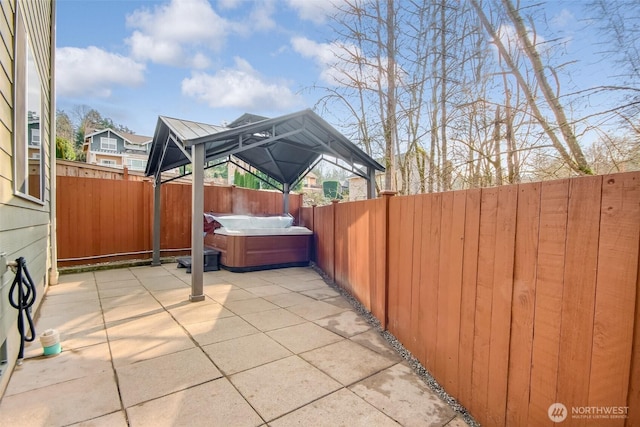 view of patio featuring a fenced backyard, a hot tub, and a gazebo