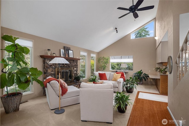 living room featuring high vaulted ceiling, a stone fireplace, ceiling fan, and stairs