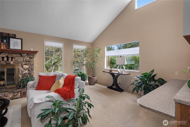 carpeted living room with a stone fireplace and high vaulted ceiling