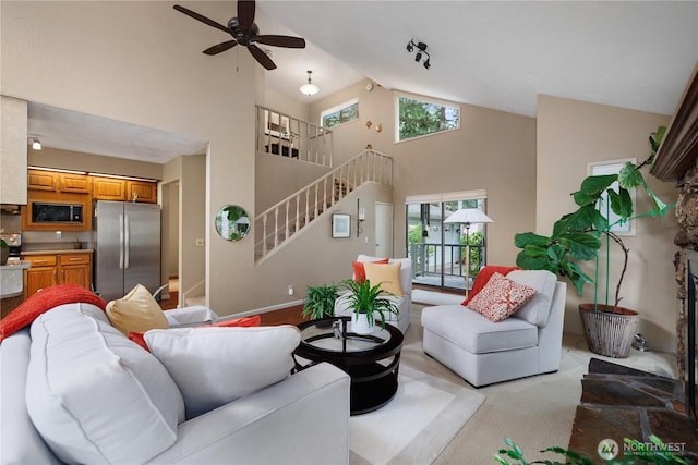 living room featuring stairs, high vaulted ceiling, ceiling fan, and light carpet