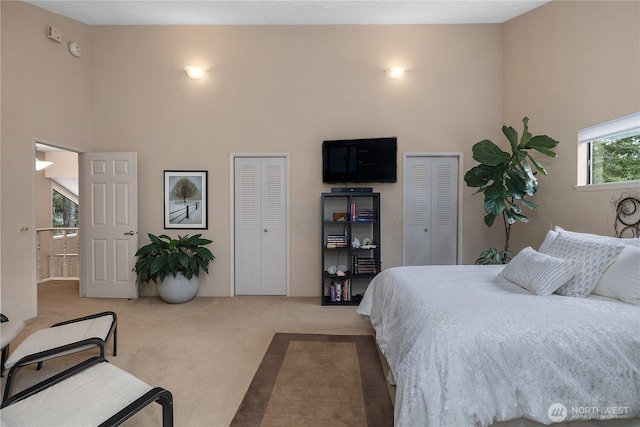 bedroom with multiple closets, a high ceiling, and carpet flooring