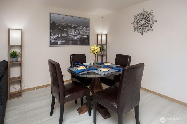 dining space with light wood finished floors and baseboards