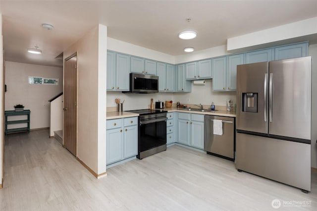 kitchen featuring blue cabinetry, appliances with stainless steel finishes, light countertops, and a sink