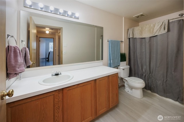 bathroom featuring curtained shower, visible vents, toilet, vanity, and wood finished floors