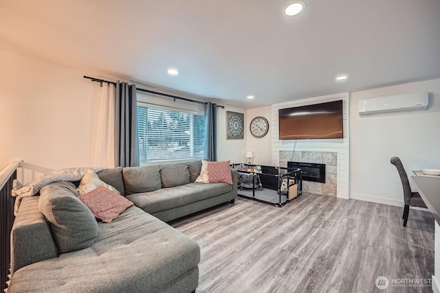 living room with wood finished floors, baseboards, a wall mounted AC, recessed lighting, and a tiled fireplace