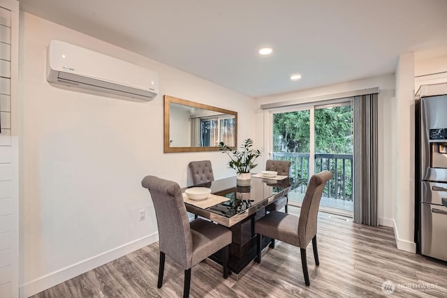 dining room with recessed lighting, baseboards, an AC wall unit, and wood finished floors