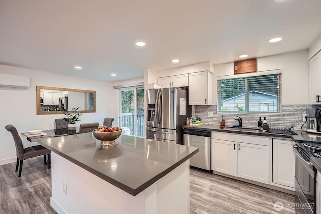 kitchen with a sink, stainless steel appliances, an AC wall unit, dark countertops, and tasteful backsplash