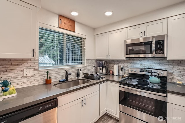 kitchen with a sink, dark countertops, appliances with stainless steel finishes, and white cabinets