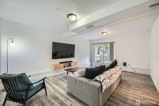 living area featuring visible vents, baseboards, and wood finished floors