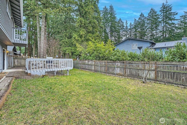 view of yard featuring a deck, a fenced backyard, and a garage