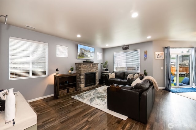 living room with dark wood-style floors, recessed lighting, baseboards, and a stone fireplace