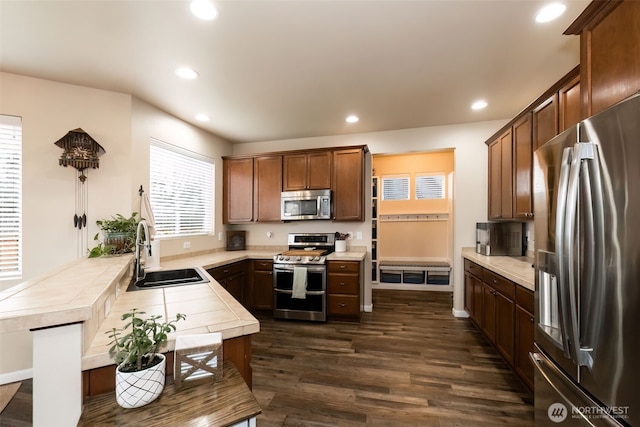 kitchen with stainless steel appliances, tile counters, a sink, and recessed lighting