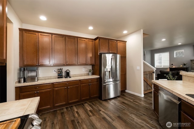 kitchen with tile countertops, appliances with stainless steel finishes, dark wood-style flooring, and recessed lighting