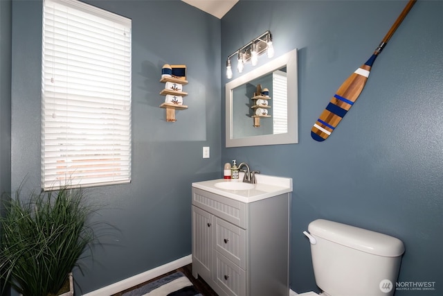 bathroom with toilet, baseboards, and vanity