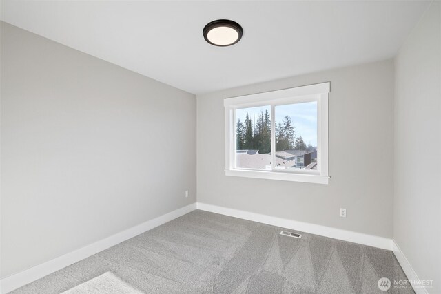 carpeted spare room with visible vents and baseboards