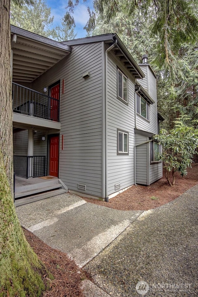 view of side of property featuring a balcony, crawl space, and a chimney