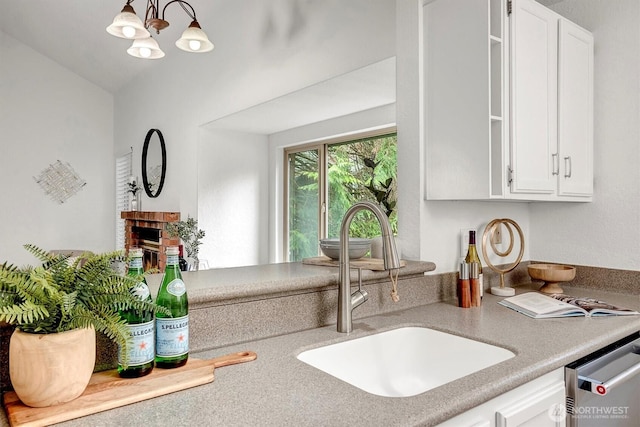 kitchen featuring a fireplace, a sink, white cabinets, light countertops, and dishwasher