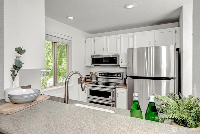 kitchen with white cabinets, appliances with stainless steel finishes, a textured ceiling, a sink, and recessed lighting