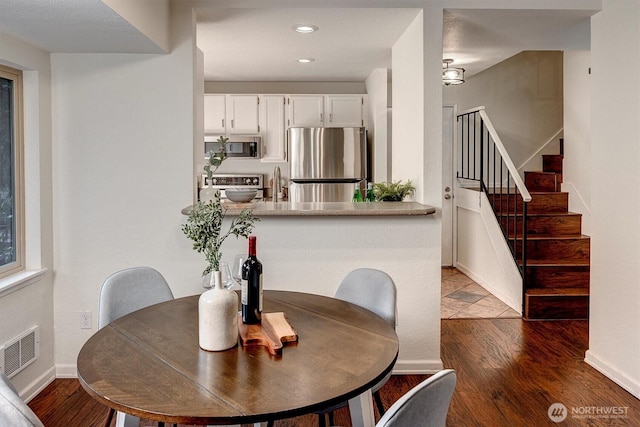 dining room with baseboards, visible vents, stairway, wood finished floors, and recessed lighting