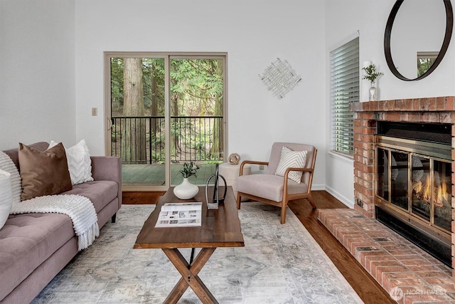 living room with a brick fireplace, wood finished floors, and baseboards