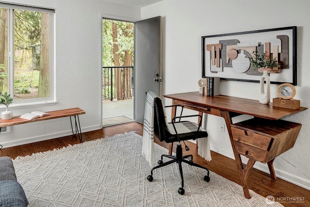 office featuring a textured wall, wood finished floors, and baseboards