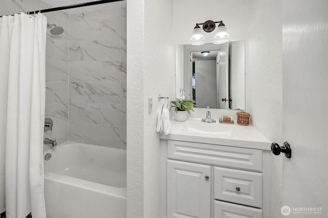 full bath with vanity, shower / bath combo with shower curtain, and a textured wall