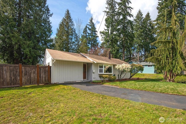 single story home with a front lawn, a chimney, fence, and aphalt driveway