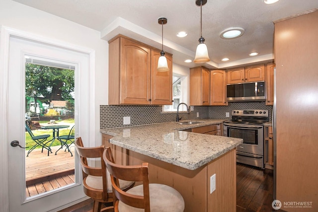 kitchen featuring stainless steel appliances, a sink, a peninsula, and decorative backsplash