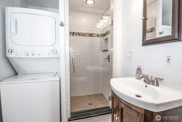 full bath featuring stacked washer and dryer, vanity, and a stall shower