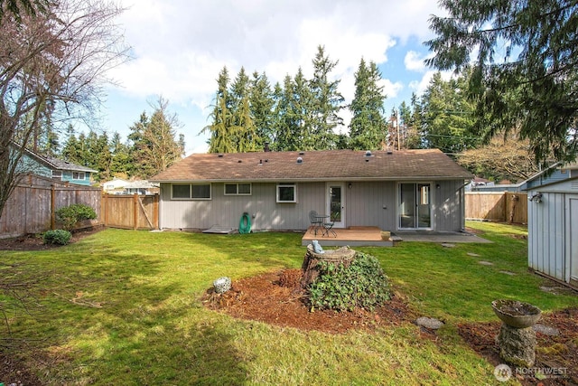 rear view of property with an outbuilding, a fenced backyard, and a yard