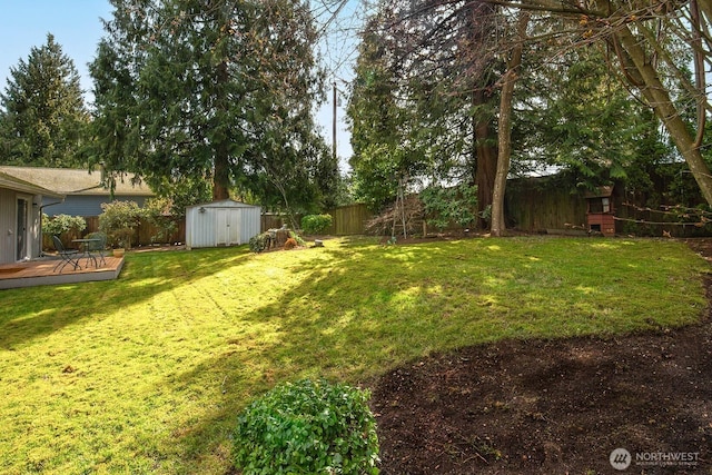 view of yard with a fenced backyard, an outdoor structure, a wooden deck, and a shed