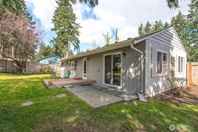 rear view of property with a yard, fence, a deck, and a patio