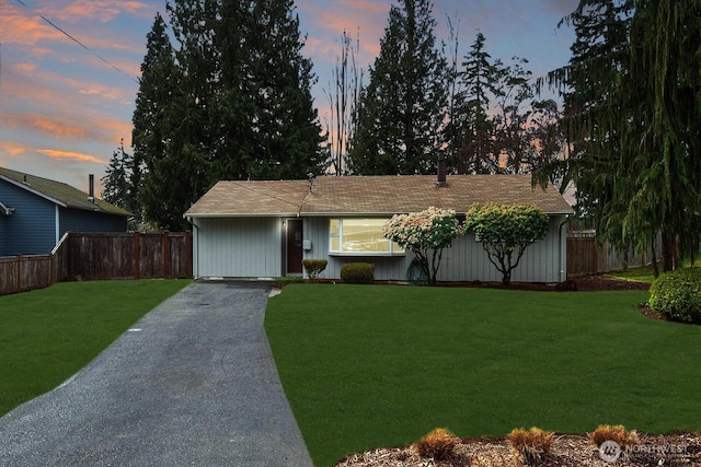 ranch-style house with driveway, a front yard, and fence