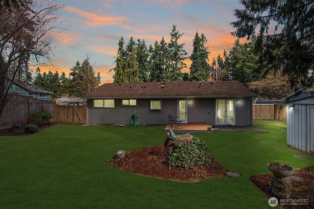 rear view of house with an outbuilding, a fenced backyard, and a yard