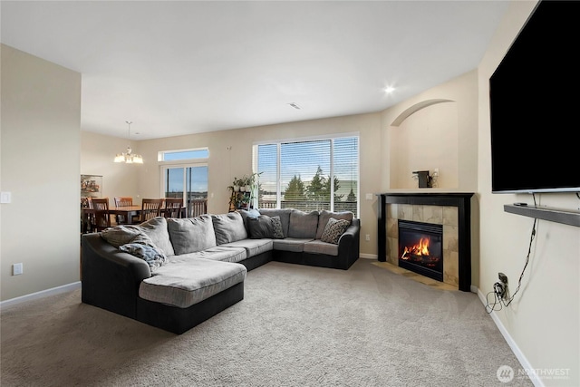 carpeted living area featuring visible vents, a tiled fireplace, a notable chandelier, and baseboards