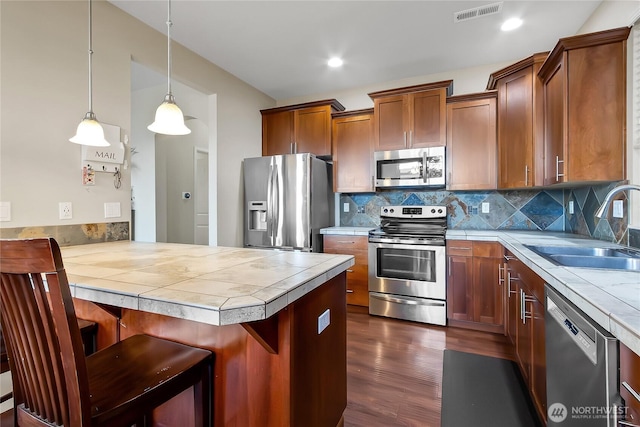 kitchen with tile counters, visible vents, appliances with stainless steel finishes, a sink, and a peninsula