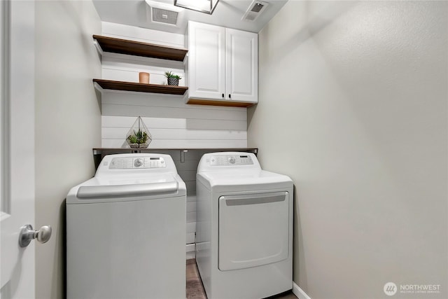 laundry area with visible vents, separate washer and dryer, and cabinet space